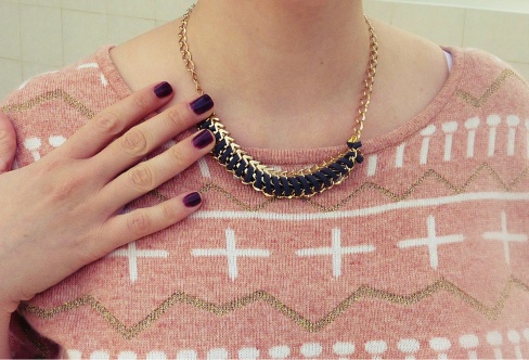 Close up photo of the sweater and a gold and suede necklace